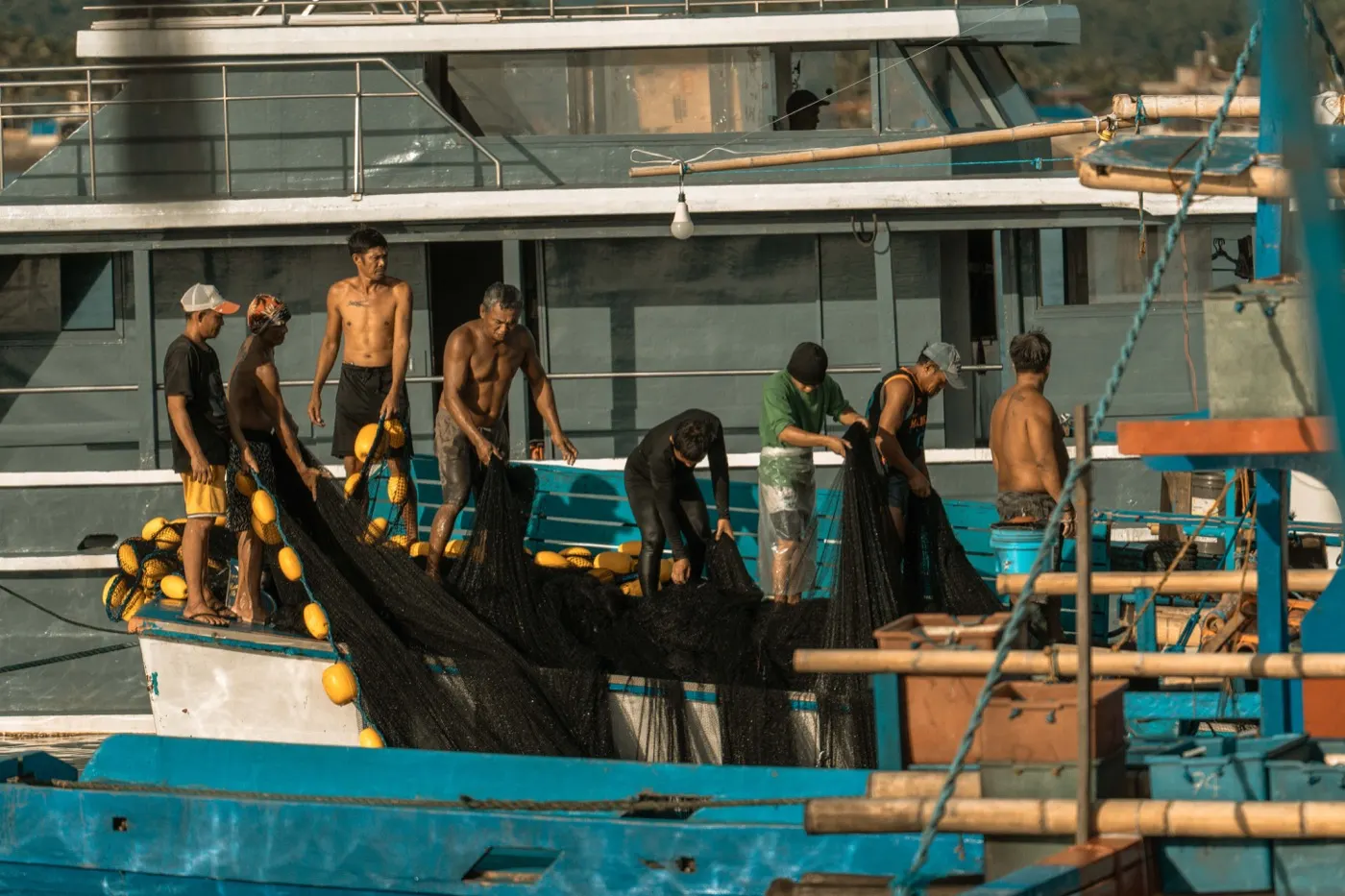 Sekumpulan nelayan mengurus jaring di atas bot